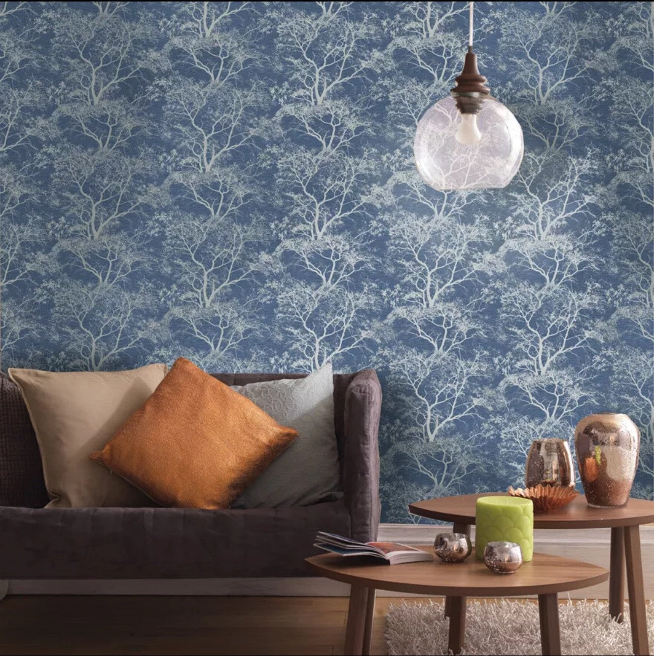 Holden Decor Whispering Trees Wallpaper in Blue Sparkle featured in a stylish living room setting with decorative cushions.